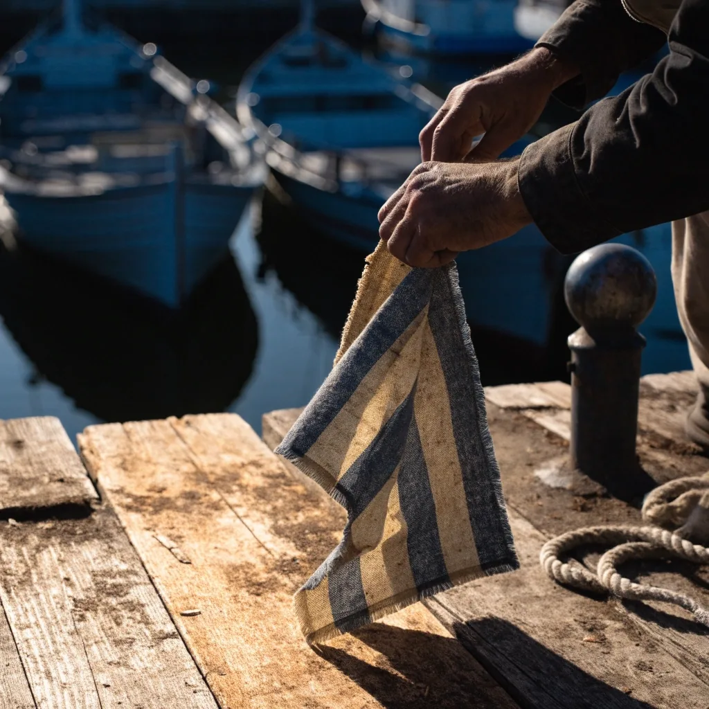 Paño de señales desplegado sobre madera de muelle con luz dura de mañana